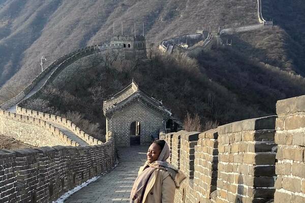 Bernice Antoine smiles while standing on a stone walkway atop the Great Wall of China.